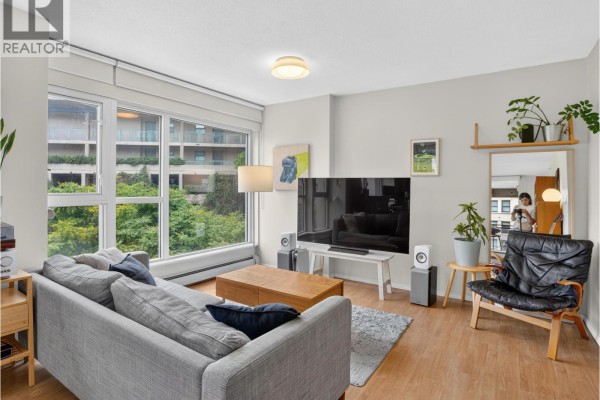 Dining table and chairs, fireplace, and bookshelves in an open-plan living area. - 602 183 Keefer Place, Vancouver