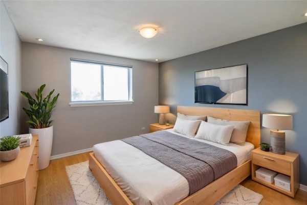 Bedroom with a king-size bed, wooden furniture, and grey accent wall. - 602 250 Wellington Crescent, Winnipeg