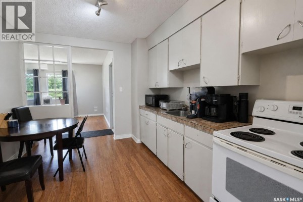 Kitchen with white cabinets, laminate countertops, and a dining table. - 602 28th Street E, Prince Albert