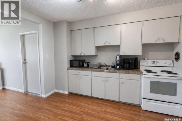 Kitchen with white cabinets, white stove, and hardwood-style flooring. - 602 28th Street E, Prince Albert