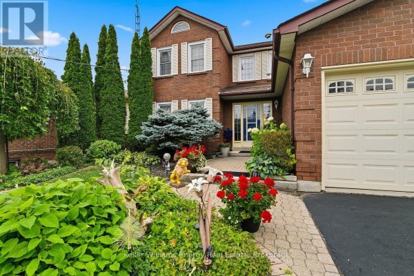 Front view of the red brick house with a walkway and flower beds. - 602 Carlisle Street, Cobourg