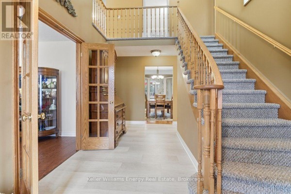 Foyer with a grand staircase, wood trim, and double doors leading to a dining room. - 602 Carlisle Street, Cobourg