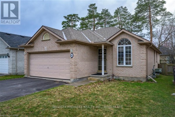 Side exterior view of a light brick bungalow with a double garage door and evergreen trees. - 602 Sprucewood Drive, London North