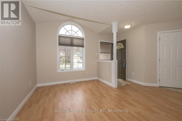 View of the living room entrance area with light wood laminate flooring and an arched window. - 602 Sprucewood Drive, London North