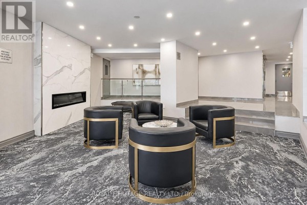 Lobby seating area with black leather chairs, a modern fireplace, and marble accents. - 603 - 10 Edgecliff Golfway, Toronto