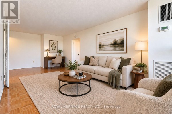 Living room with a beige sofa, coffee table, and a desk in the background. - 603 - 10 Edgecliff Golfway, Toronto