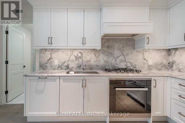 White kitchen cabinets with marble backsplash, stainless steel sink, and gas stove. - 603 - 1451 Wellington Street W, Ottawa