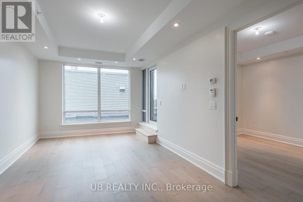 Empty room with large windows, white walls, and grey wood floors. - 603 - 1451 Wellington Street W, Ottawa