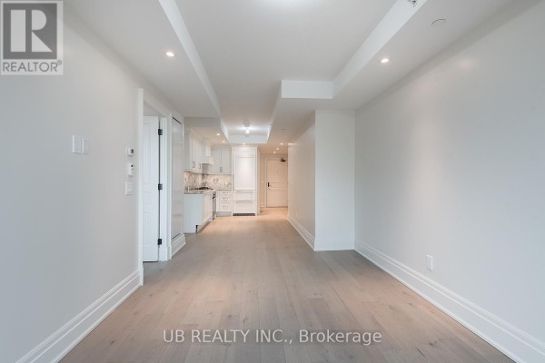 Wide view of an apartment living area showing the kitchen and a hallway. - 603 - 1451 Wellington Street W, Ottawa