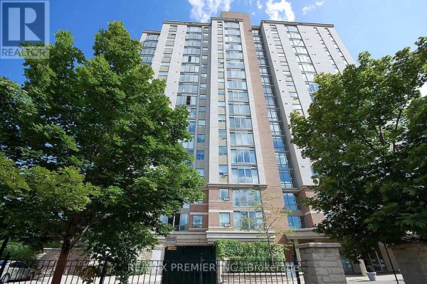 A tall apartment building with many windows, surrounded by green trees. - 603 - 200 Burnhamthorpe Road E, Mississauga