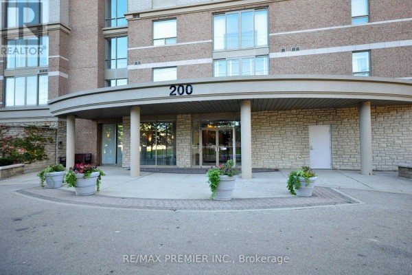 The main entrance of a building with a large curved overhang and stone facade. - 603 - 200 Burnhamthorpe Road E, Mississauga