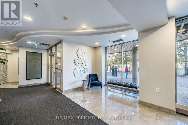A building lobby with marble floors, a dark blue chair, and a long bench. - 603 - 200 Burnhamthorpe Road E, Mississauga