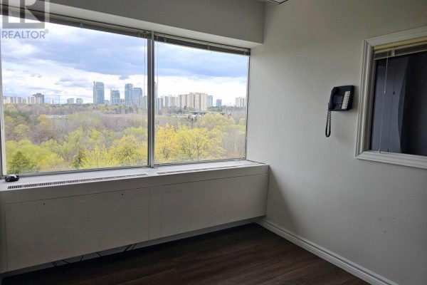 Office space corner with large windows, a wall-mounted phone, and dark wood flooring. - 603 - 220 Duncan Mill Road W, Toronto