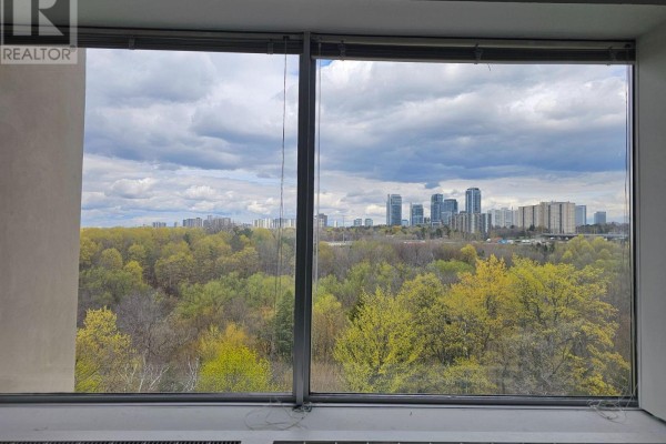 City skyline view through large windows overlooking a canopy of green and yellow trees. - 603 - 220 Duncan Mill Road W, Toronto