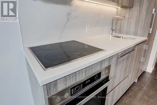 Close-up of the kitchen counter showing an induction cooktop, sink, and Miele oven. - 603 - 38 Widmer Street, Toronto