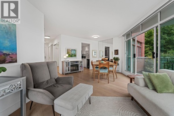 Living area with dining table, chairs, sofa, and entrance to balcony with view of buildings. - 603 130 E 2nd Street, North Vancouver