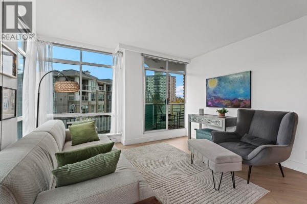 Bright living room with sofa, armchair, desk, large windows, and abstract wall art. - 603 130 E 2nd Street, North Vancouver