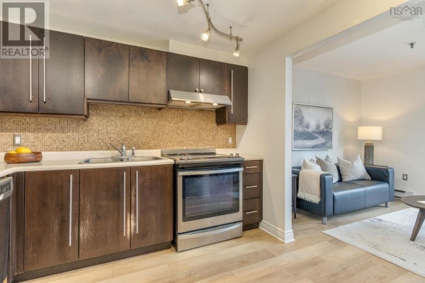 Kitchen with dark wood cabinets, stainless steel appliances, and light wood flooring. - 603 1454 Dresden Row, Halifax