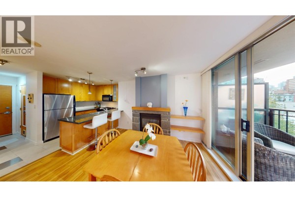 Open concept living and dining area with a fireplace and kitchen island. - 603 989 Richards Street, Vancouver