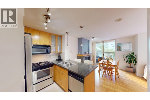 Kitchen and dining area with stainless steel appliances and a sliding glass door. - 603 989 Richards Street, Vancouver