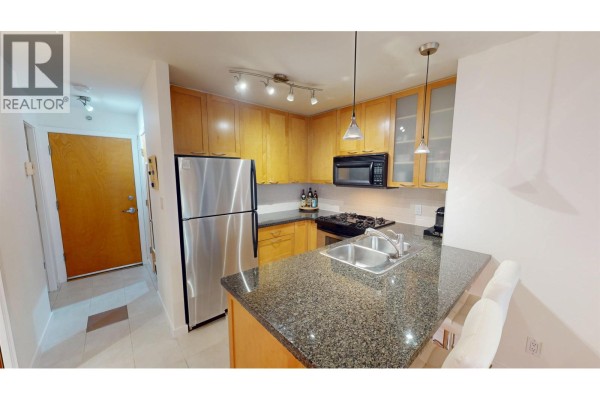 Kitchen with wood cabinets, granite counters, and a view of the entry hallway. - 603 989 Richards Street, Vancouver