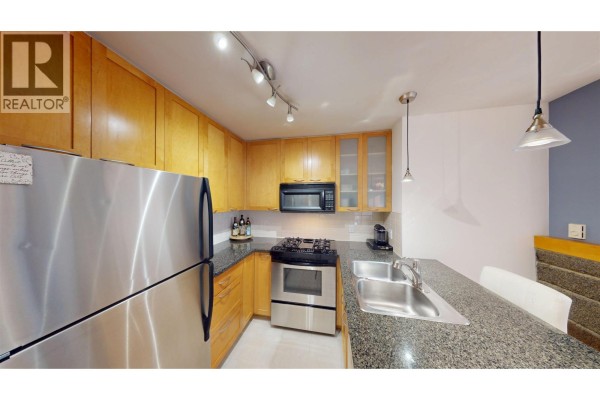 Kitchen featuring stainless steel appliances, wood cabinetry, and a breakfast bar. - 603 989 Richards Street, Vancouver