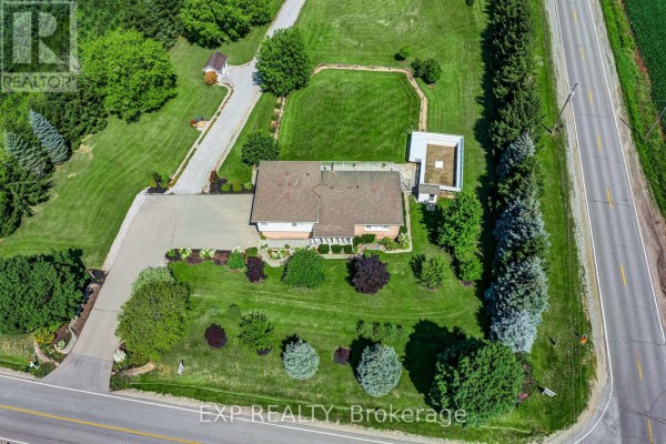 Overhead view of the house and its landscaped front yard, bordered by trees and a paved driveway. - 6030 Doane Road, East Gwillimbury