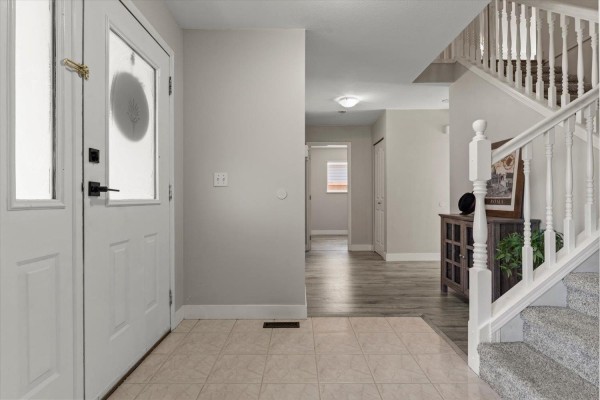 Interior view of the foyer with a staircase, tiled floor, and hallway leading deeper into the house. - 6033 Glenroy Drive, Sardis South, Chilliwack