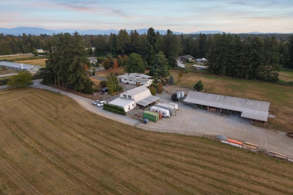 Overhead view of the farmstead, showing outbuildings, RVs, and neatly mown fields. - 6035 Bradner Road, Abbotsford