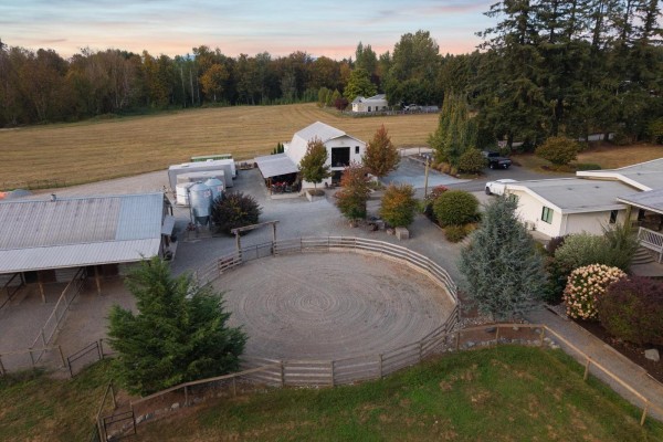View of a circular riding arena with fences, surrounded by farm buildings and landscaping. - 6035 Bradner Road, Abbotsford
