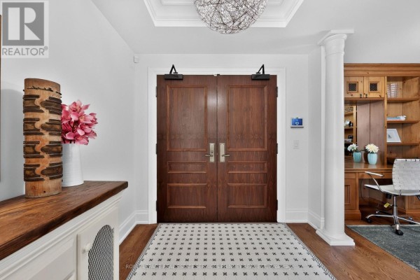 Foyer with dark wood double doors, tile floor, and built-in wooden cabinets on the right. - 604 - 111 Forsythe Street, Oakville