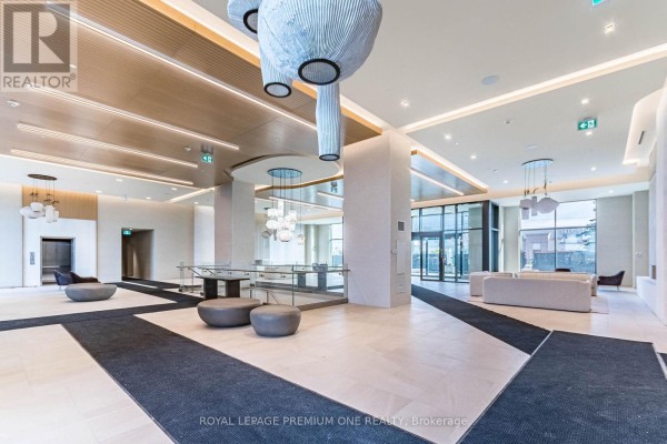 Spacious condo lobby with cream tile floors, wood accents, and modern seating. - 604 - 8960 Jane Street, Vaughan