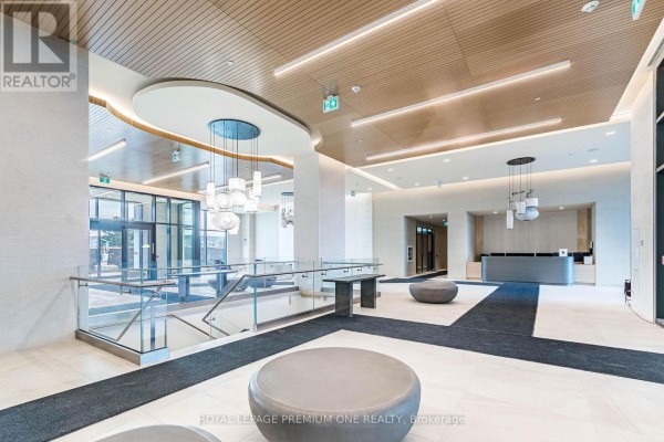 Contemporary condo lobby featuring a glass railing, unique light fixtures, and seating. - 604 - 8960 Jane Street, Vaughan
