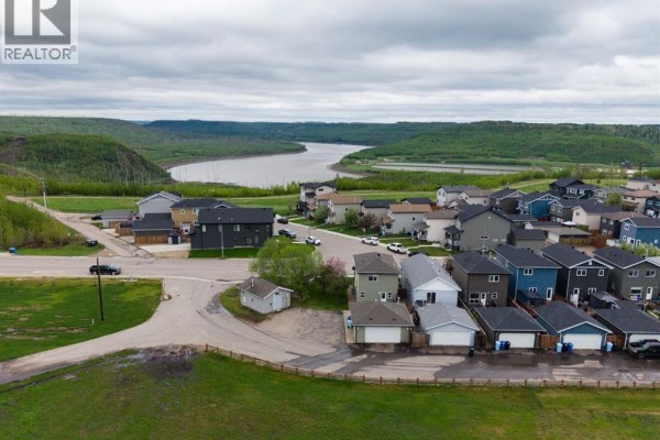 Aerial view of a suburban neighborhood with houses, streets, and a river in the background. - 604 Athabasca Avenue, Fort Mcmurray
