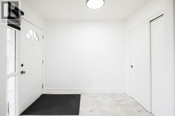 Interior of a bright entryway with a white door, black mat, and closet. - 604 Athabasca Avenue, Fort Mcmurray