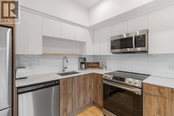 Modern kitchen with white cabinetry, stainless steel appliances, and quartz countertops - 604 Cawston Avenue Unit# 404, Kelowna