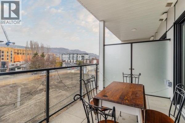 Balcony with a wooden table and chairs, overlooking the surrounding area - 604 Cawston Avenue Unit# 404, Kelowna