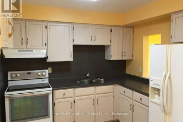 U-shaped kitchen with white cabinets, black countertops, white appliances including a stove and refrigerator, and yellow walls. - 6043 Chidham Crescent, Mississauga