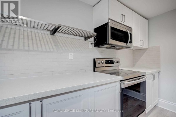 Close-up of a stainless steel range hood over a stove in a white kitchen. - 604a Queen Street W, Toronto