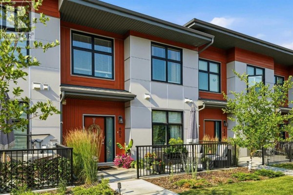 Three-story townhouse building facade featuring wood and grey panels and large windows. - 605, 400 Belmont Street Sw, Calgary