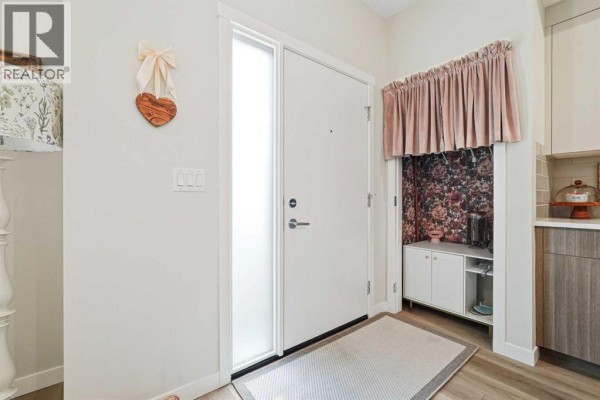 Interior entryway with a white door, frosted side panel, and a small white cabinet. - 605, 400 Belmont Street Sw, Calgary
