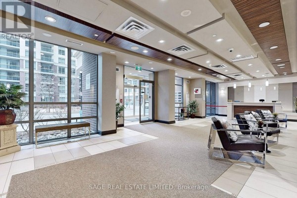 Lobby area of the apartment building with a reception desk, seating, and large windows. - 605 - 1 Michael Power Place, Toronto