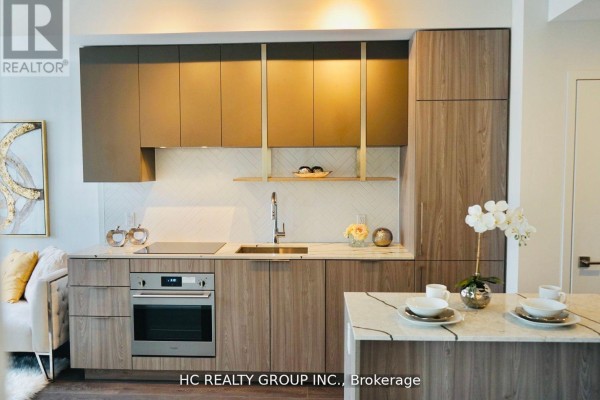 Contemporary kitchen with wood cabinets, stainless steel oven, and marble island. - 605 - 15 Holmes Avenue, Toronto