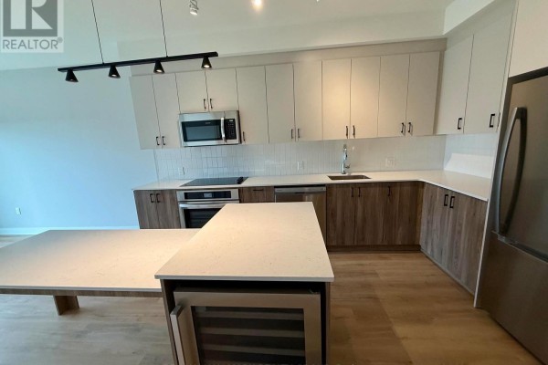 Modern kitchen with two-tone cabinets, stainless steel appliances, and an island with wine fridge. - 605 - 275 Carling Avenue, Ottawa