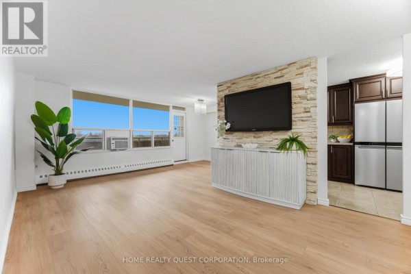 Living room with stone accent wall, modern cabinetry, and large windows - 605 - 3120 Kirwin Avenue, Mississauga