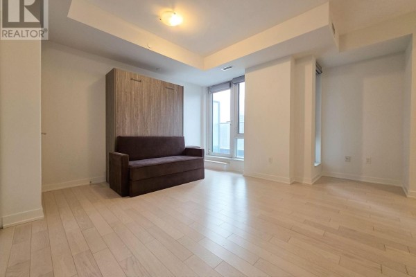Spacious living area with a foldable sofa bed and large windows overlooking the city. - 605 - 330 Richmond Street W, Toronto