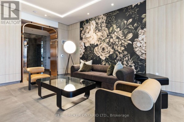 Close-up of lobby seating area with a dark sofa, coffee table, and patterned wallpaper. - 605 - 556 Marlee Avenue, Toronto
