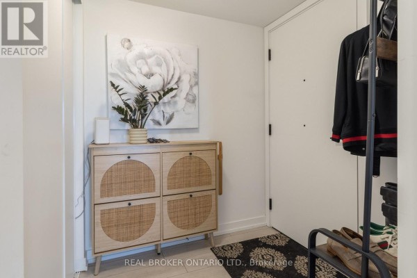 Entryway with a white door, light wood furniture, potted plant, and artwork on the wall. - 605 - 556 Marlee Avenue, Toronto