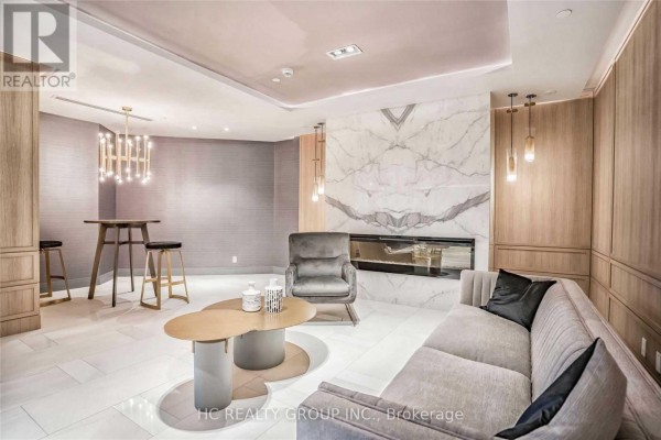 Lobby seating area with grey sofa, chairs, modern coffee table and marble fireplace. - 605 - 621 Sheppard Avenue E, Toronto