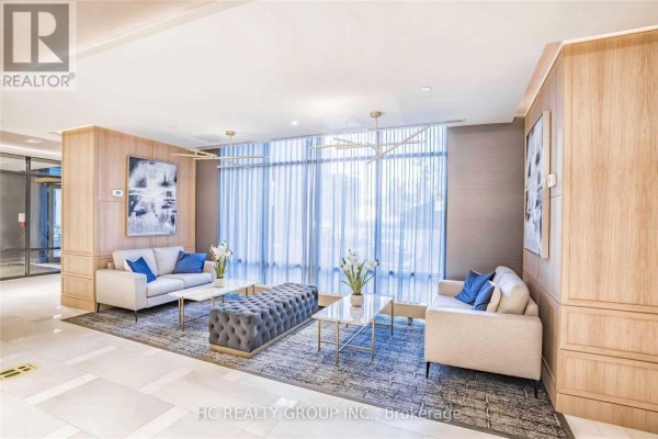 Building lobby with two beige sofas, glass coffee tables, and blue accent pillows. - 605 - 621 Sheppard Avenue E, Toronto